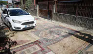 Asfaltlanmayan yoldaki çukurlar halılarla kapatıldı