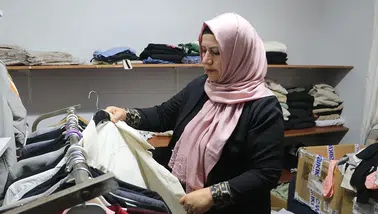Kadın muhtar mahallelinin hem derdini dinliyor hem terziliğini yapıyor