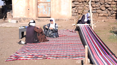 Evinin bahçesindeki tezgahta asırlık yöntemle kilim dokuyor