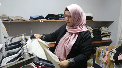 Kadın muhtar mahallelinin hem derdini dinliyor hem terziliğini yapıyor
